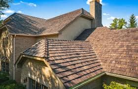 Stone home with a brown architectural asphalt shingle roof