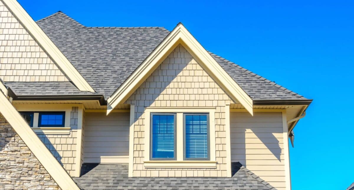 Craftsman home with a gray architectural shingle roof and gable dormer against a blue sky