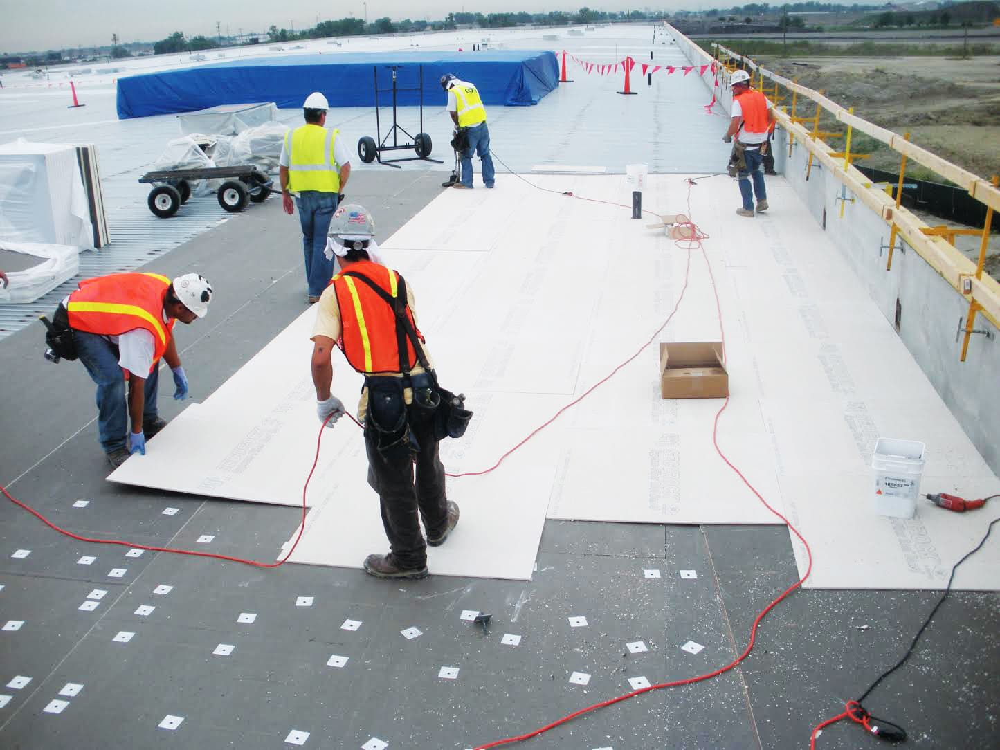 Commercial roofing crew installing membrane on a large flat commercial roof