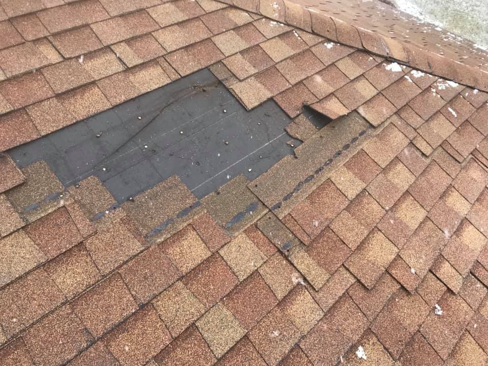 Roof with missing shingles exposing the underlayment, needing repair